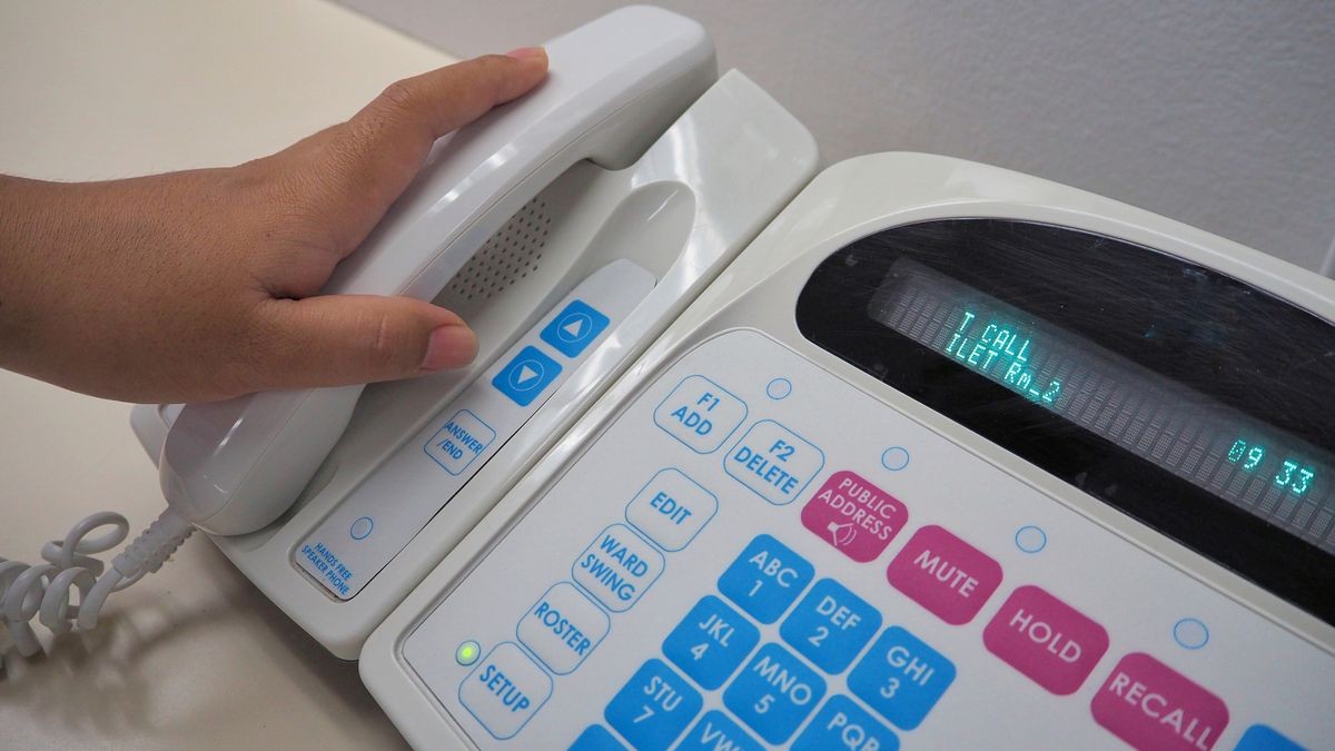 nurse's hand holding phone from electronic communication equipment.Equipment for nurse or staff when patient call for help.